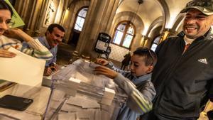 Un padre vota junto a su hijo en el edificio histórico de la Universitat de Barcelona, este domingo.