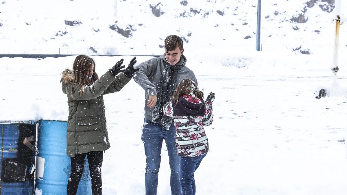 Los hermanos Claudia, Julio y Bárbara Apéstigue juegan con la nieve en la gasolinera del Huerna.