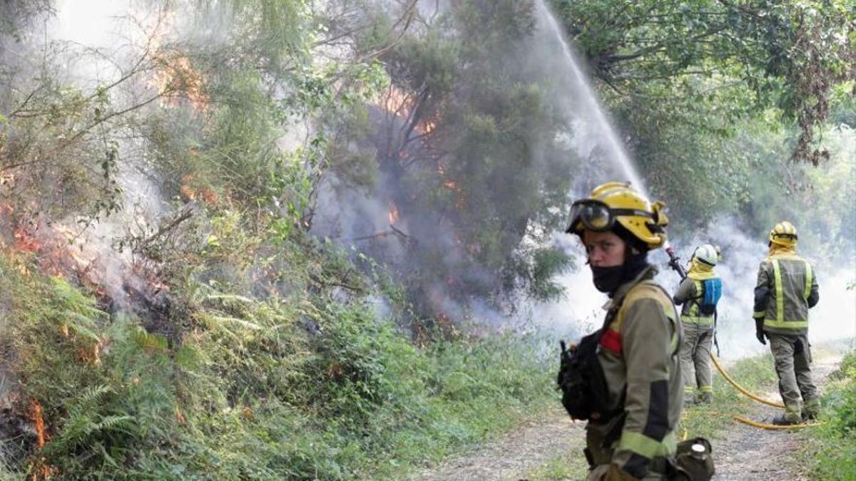 Una brigada, ayer, en un incendio en Samos (Lugo). A la izquierda, imagen de satélite de la tormenta y abajo, mapa de los rayos caídos.