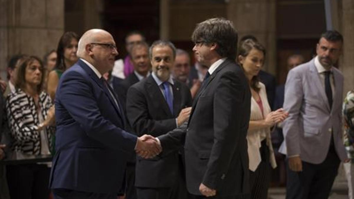 Carles Puigdemont da la mano al destituido 'conseller' Jordi Baiget, ayer.