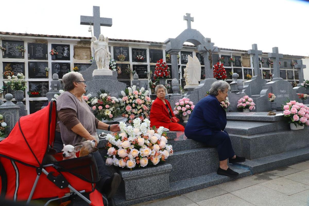 Varias señoras, junto a las tumbas de sus seres queridos.