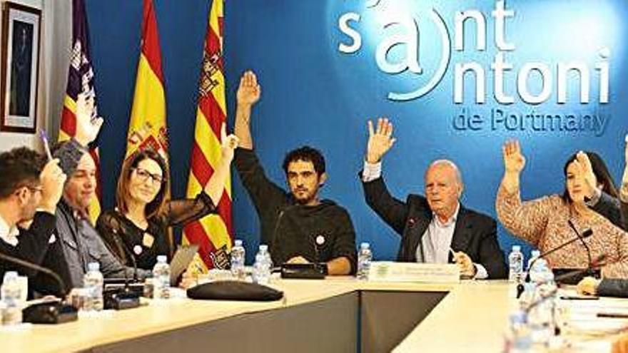 Los miembros del gobierno alzan el brazo durante una votación en el pleno extraordinario de ayer.