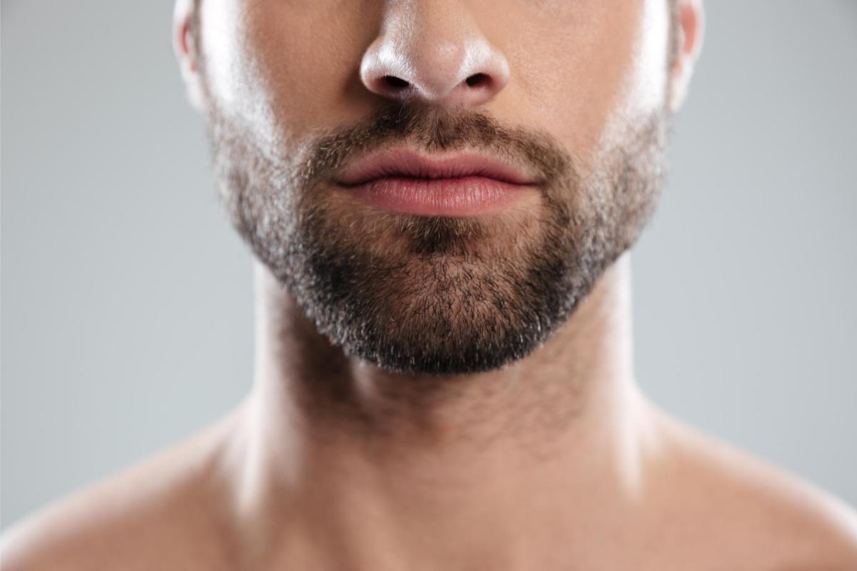 Cropped image of a half mans face with beard isolated over white background Imagen recortada de la mitad del rostro de un hombre con barba,