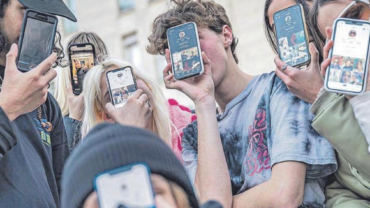 Jóvenes muestran sus perfiles de redes sociales en sus móviles.