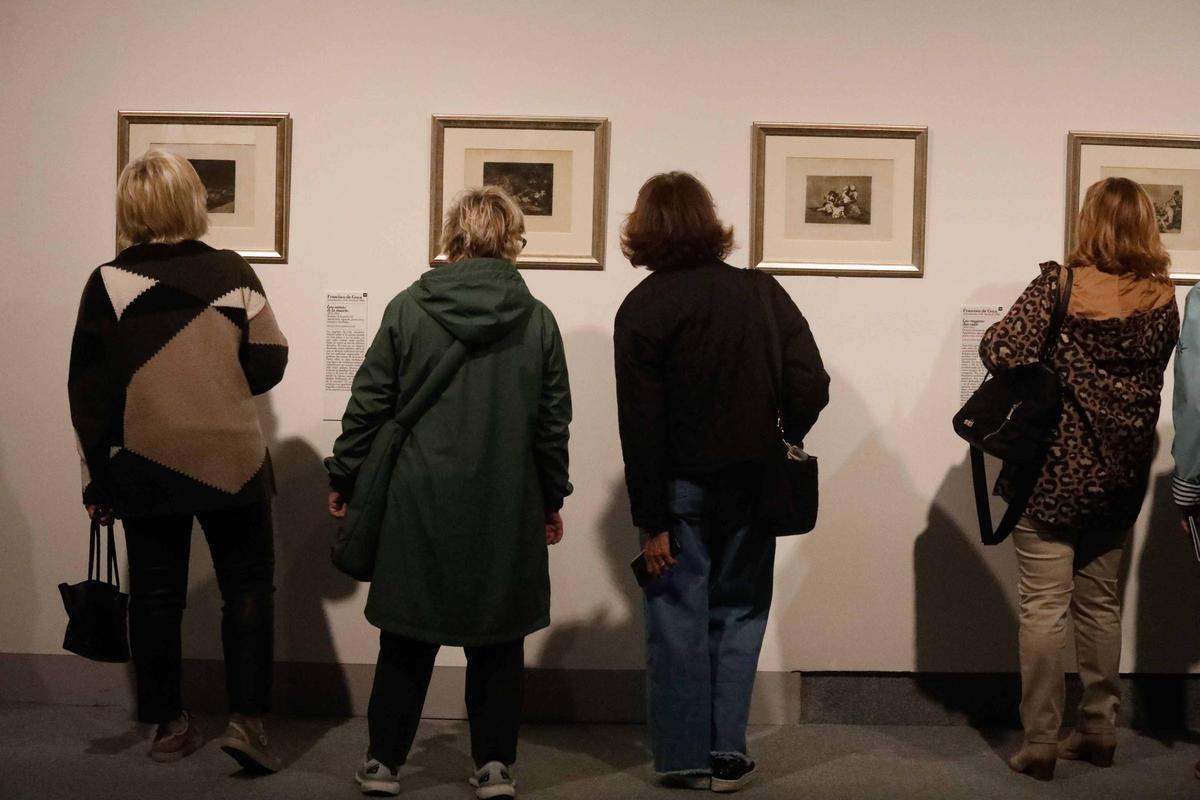 Cuatro mujeres contemplan los grabados de Goya de la muestra del Niemeyer.
