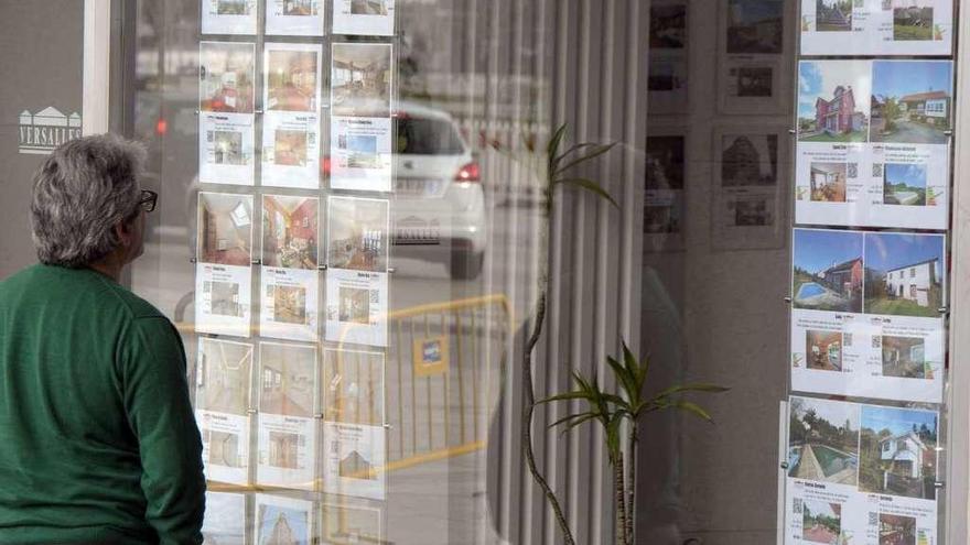 Un hombre mira los anuncios de pisos en venta en el escaparate de una inmobiliaria de A Coruña.