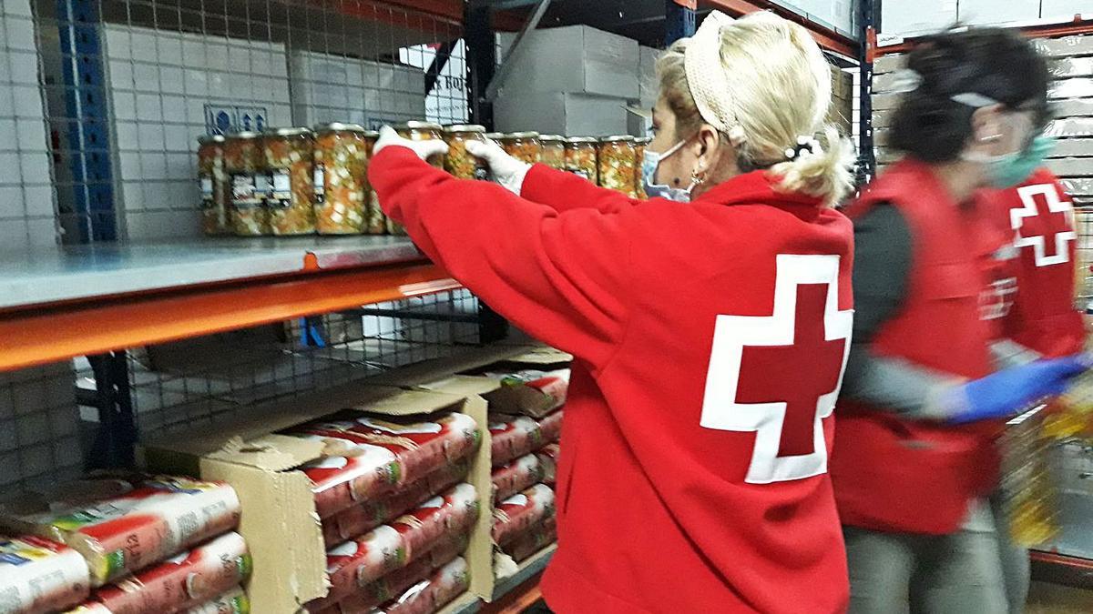 Voluntarios de Cruz Roja colocan los alimentos que distribuyen a las familias.