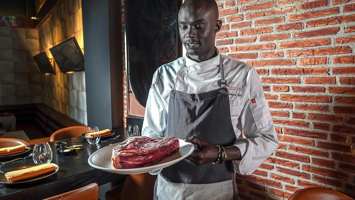 El chef Babacar Fall con una de las carnes que prepara.