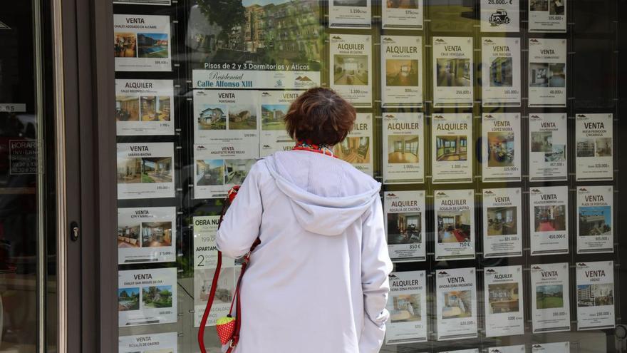 Una mujer observa los anuncios de ventas y alquileres en una inmobiliaria de Vigo. |   // ALBA VILLAR