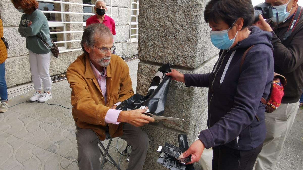 Paco Ferreira corta trozos de la pancarta negra de la Plataforma.