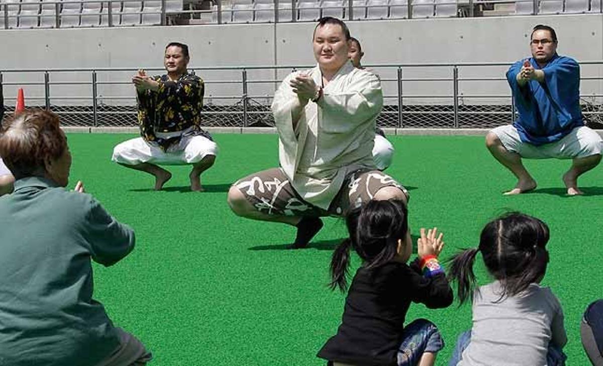 El gran campió de sumo, el mongol Hakuho, amb altres lluitadors, mostren un exercici a persones evacuades per por a la radiació de la central de Fukushima, a l’estadi Ajinomoto, a Tòquio (Japó).