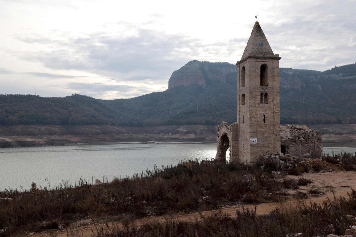 Esta fotografía tomada el 15 de enero de 2024 muestra la iglesia de Sant Roma de Sau en la orilla del estiaje del embalse de Sau, situado en la provincia de Girona en Cataluña. Cataluña lucha contra una sequía histórica desde hace tres años y algunos residentes ya experimentan restricciones de agua en su vida diaria.