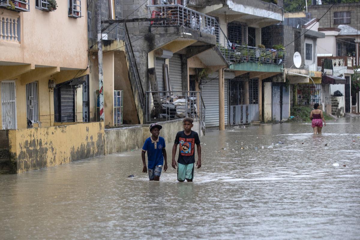 Personas caminan por una calle inundada en el barrio Manoguayabo este viernes, en Santo Domingo (República Dominicana). EFE/Orlando Barría. Se añaden fotos del día y video editado con locución
