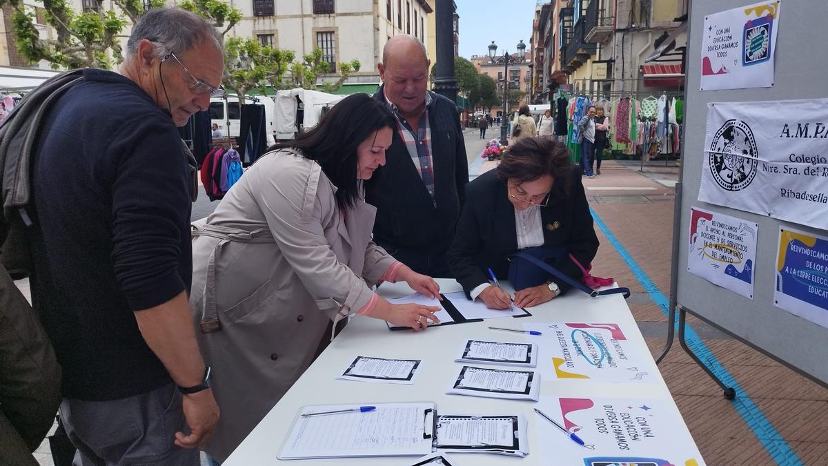 Vecinos, firmando a favor del colegio en el mercado semanal de Ribadesella.