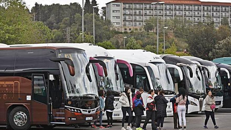 A la imatge de dalt, autobusos aparcats a Fontajau. A baix, una visita turística a Girona davant l&#039;església de Sant Feliu.