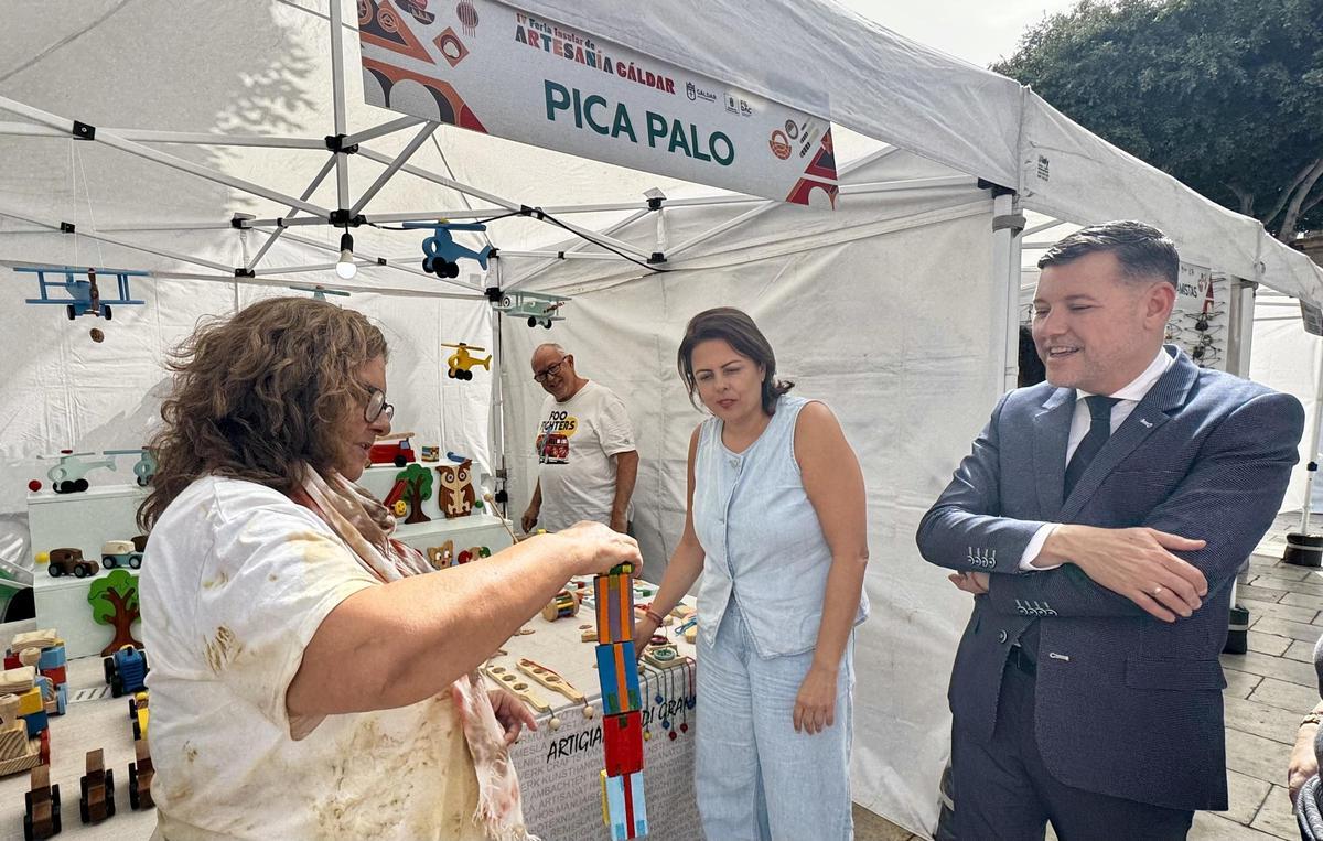 Una de las artesanas muestra su trabajo a Minerva Alonso y Teodoro Soa, en la Feria de Artesanía Norte.