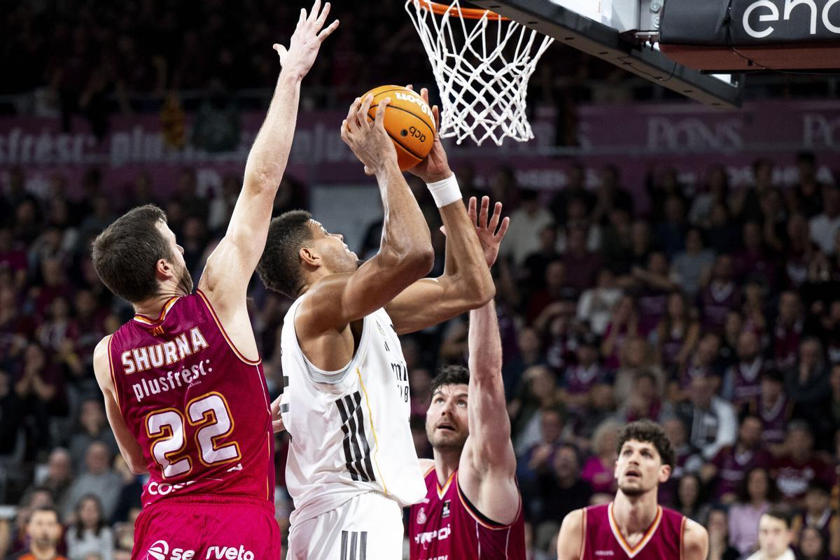 El pívot del Real Madrid Edy Tavares (2i) entra a canasta ante los jugadores de Hiopos Lleida John Shurna (i) y Gyorgy Goloman durante el encuentro correspondiente a la fase regular de la Liga Endesa que disputaron en el pabellón Barris Nord de Lleida. EFE/ Álex López
