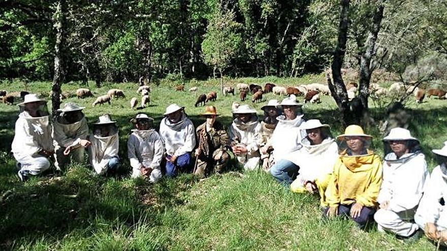 Participantes en el curso de apicultura posan en una pradera pastada por un rebaño de ovejas.