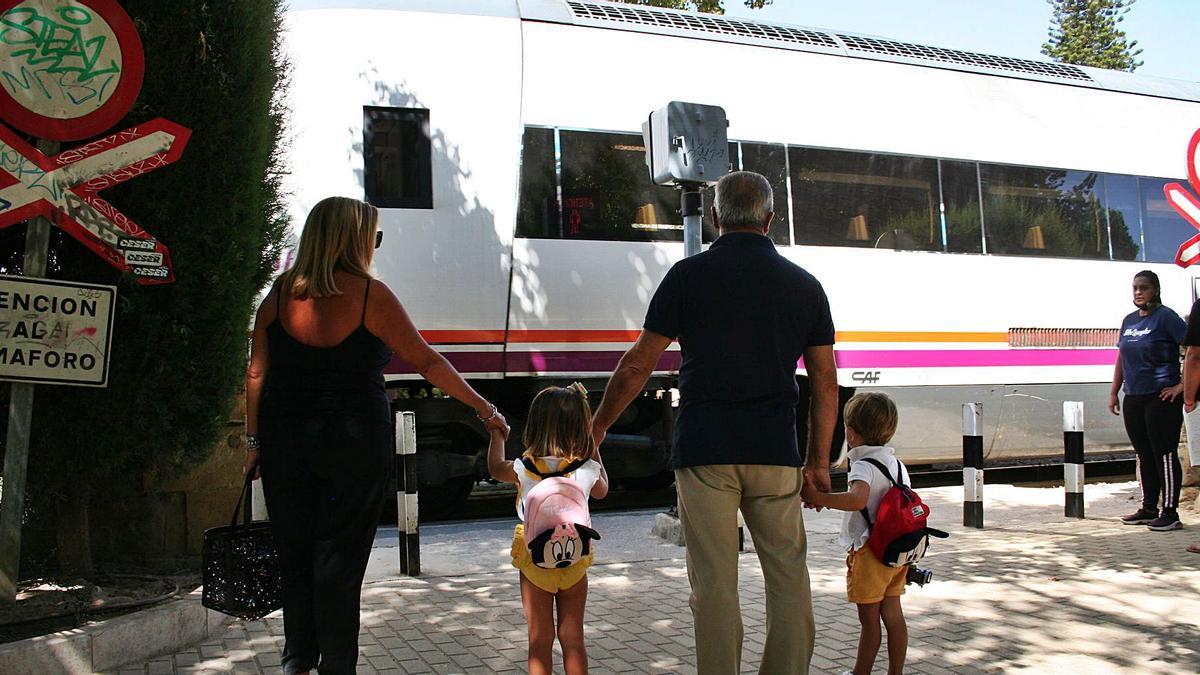 Dos escolares esperan que pase eltren para cruzar en la Alameda dela Constitución.