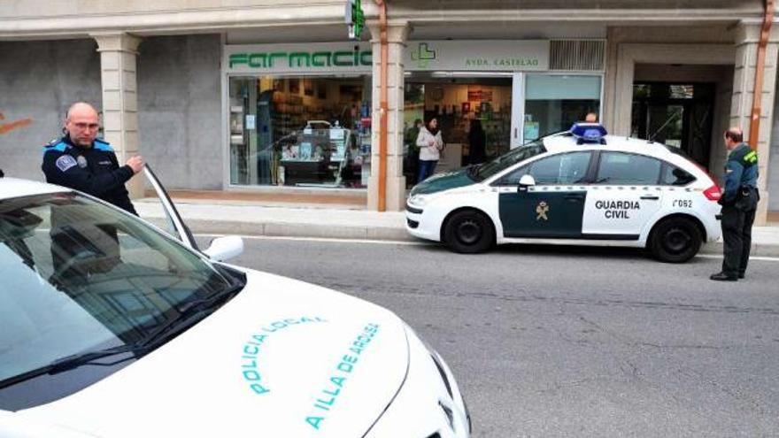 Agentes de la Policía Local de A Illa y de la Guardia Civil, saliendo de la farmacia atracada ayer.  // I. Abella