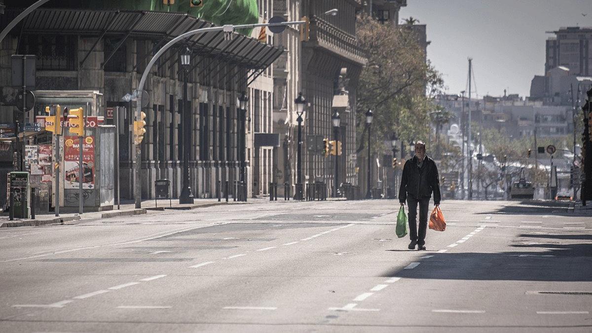Un hombre regresa de la compra por una Via Laietana completamente vacía por el estado de alarma