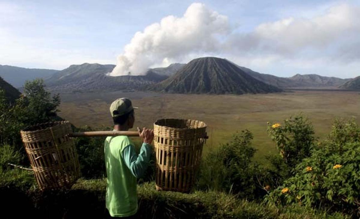 Un agricultor observa el mont Bromo, a l’illa indonèsia de Java, que ha començat a escopir petites columnes de cendra i fum. Les autoritats han decretat la màxima alerta roja davant l’activitat del volcà Bromo.