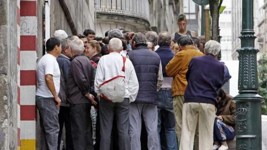 Un grupo de personas se arremolina a las puertas de un comedor social. / marta g. brea
