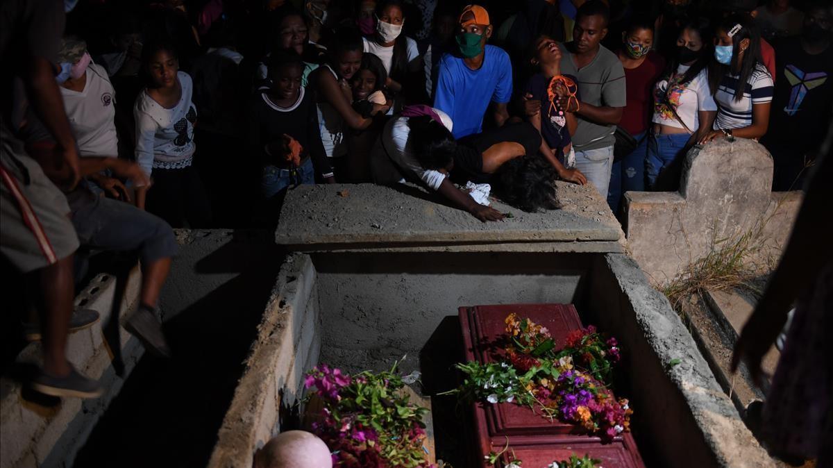 Relatives and friends of Cristalinda Goitia 36  and her son Cristian Garcia Goitia 11  mourn their deaths while attending his funeral in the common grave of La Salina cemetery on December 16  2020 in Guira  Venezuela  after both drowned in a shipwreck  - At least 20 Venezuelan migrants died when a ship heading for Trinidad and Tobago sank  the public prosecutor s office said on December 14  2020  (Photo by YURI CORTEZ   AFP)