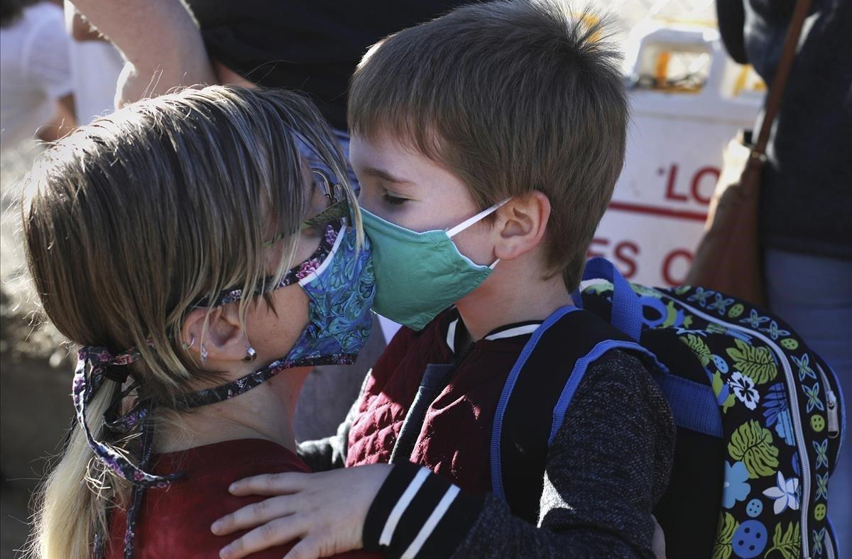 Jessica Christian le da a su hijo Tobias un beso, a través de sus máscaras faciales, mientras lo deja en la guardería en la Escuela Primaria Park, en Casper Wy, Estados Unidos.