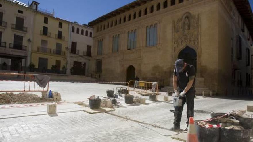 Un operario, ayer en las obras de remozado de la plaza de la Seu de Xàtiva, con la fachada del antiguo hospital al fondo.