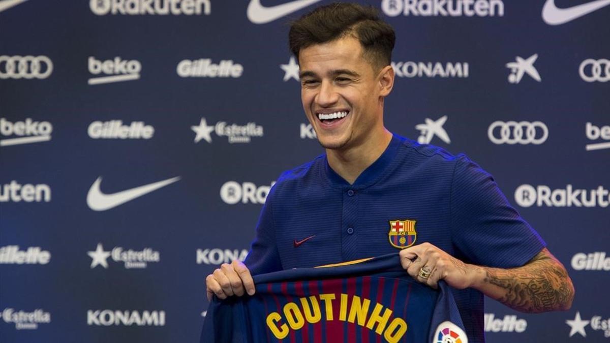 Philippe Coutinho sostiene la camiseta con su nombre durante el acto de presentación.