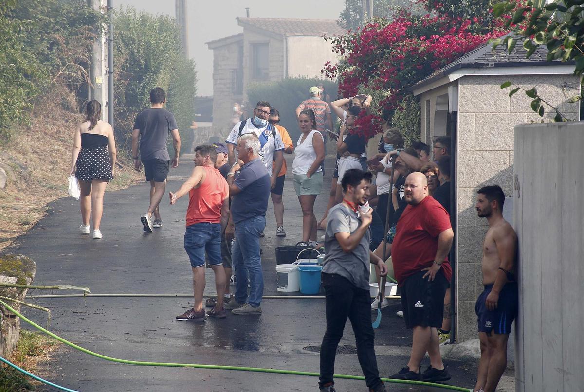 Los vecinos de la parroquia de Meira con cubos de agua y mangueras para sofocar el fuego, a 22 de agosto, en la parroquia de Meira, en Moaña, Pontevedra, Galicia (España). El fuego declarado en una zona de eucaliptos, ha obligado a cortar la autovía de O