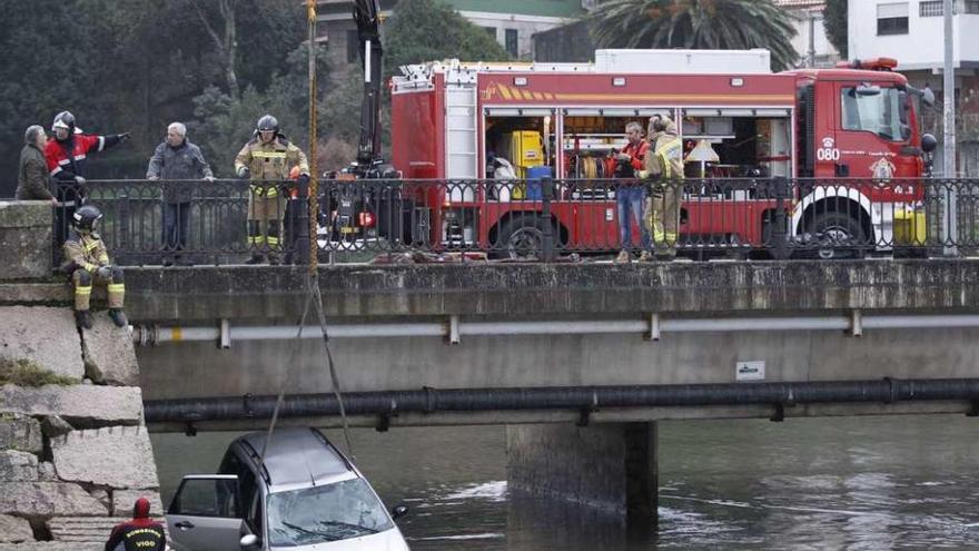 Los bomberos intentan retirar el vehículo de la desembocadura del río Lagares. // José Lores