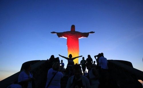 Los turistas toman fotos delante de la estatua del Cristo Redentor iluminado con los colores de la bandera nacional de Alemania en Río de Janeiro 03 de octubre 2012. La estatua iluminada celebra el aniversario de la reunificación de la Alemania, que