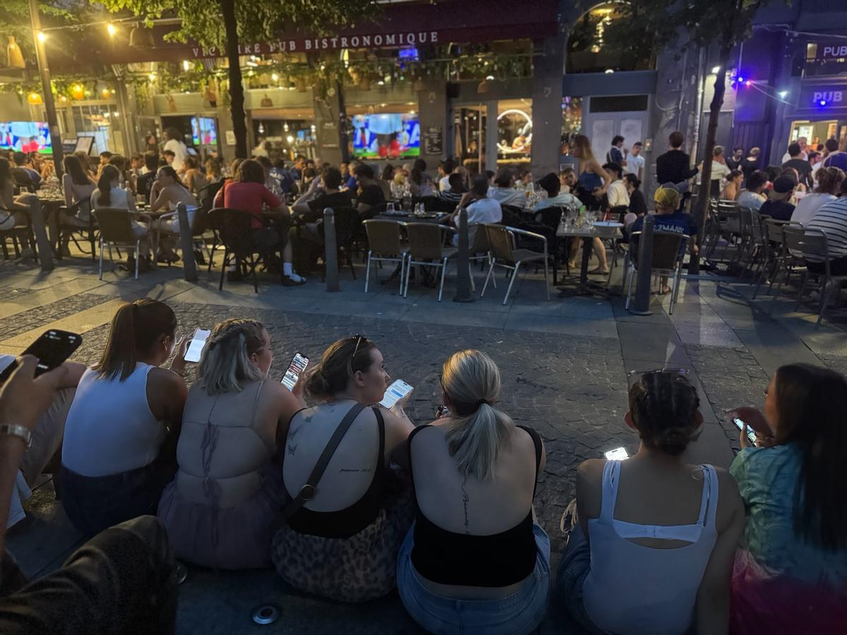 Un grupo de jóvenes sigue el partido sin olvidar la actividad de sus móviles.