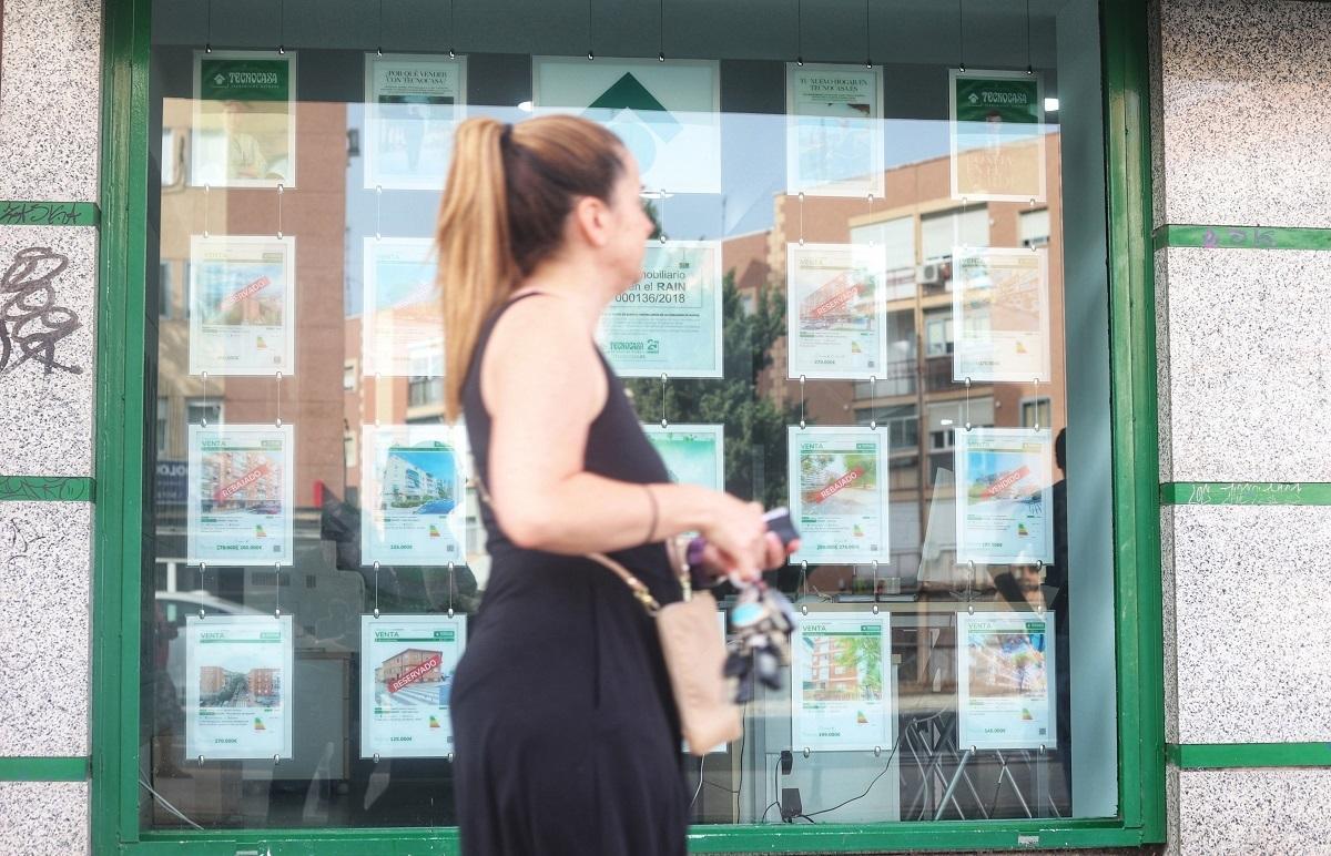 Una mujer pasa por delante del escaparate de una agencia inmobiliaria en Málaga.
