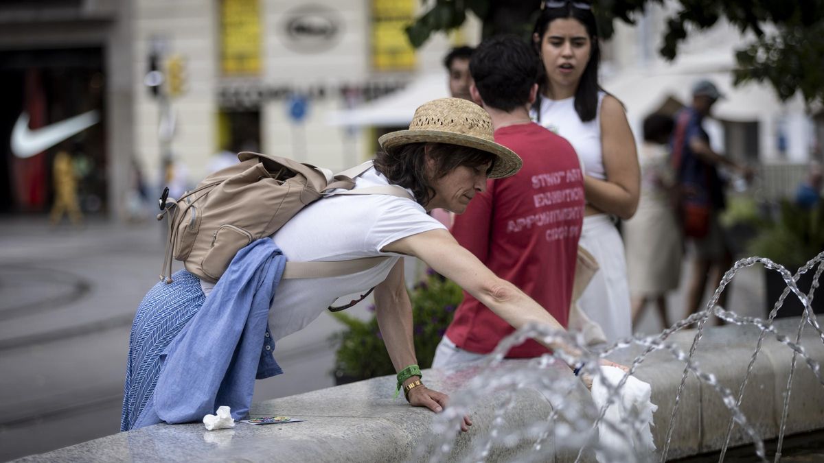 Una mujer busca refrigerarse mojando un pañuelo en la fuente de la Plaza España de Zaragoza.