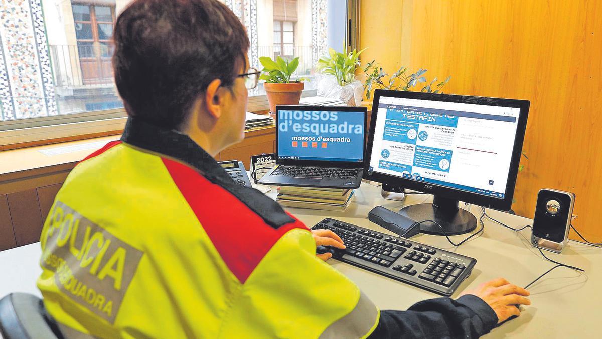 Una agent dels Mossos d'Esquadra consulta un web per evitar estafes informàtiques.