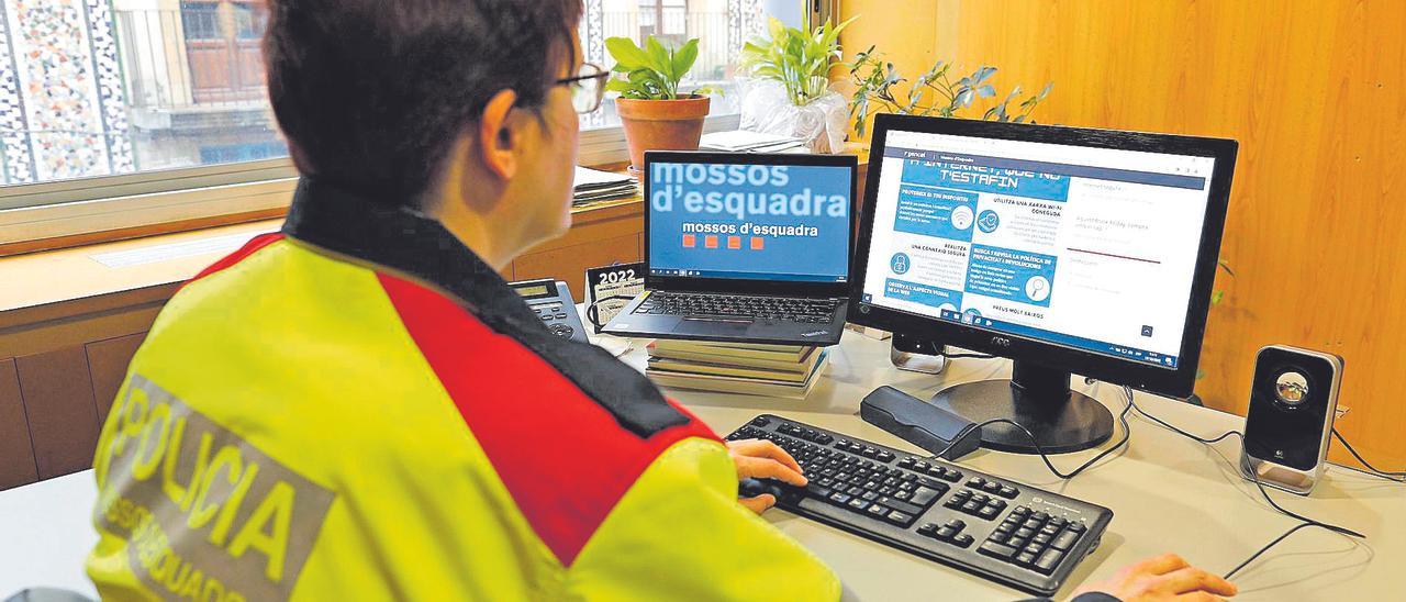 Una agent dels Mossos d'Esquadra consulta un web per evitar estafes informàtiques.