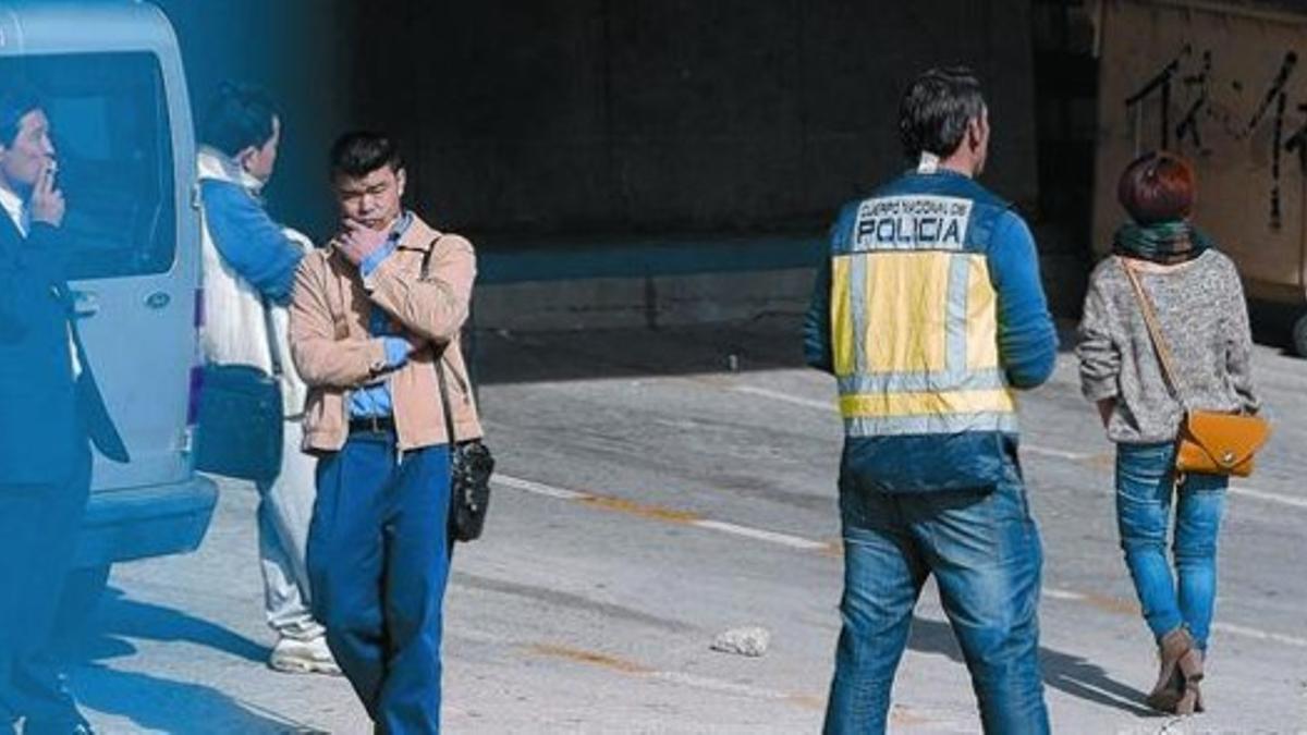 Un policía nacional, junto a varios ciudadanos chinos, en el polígono Cobo Calleja de Fuenlabrada (Madrid), donde se desarrolló parte de la operación policial, ayer.