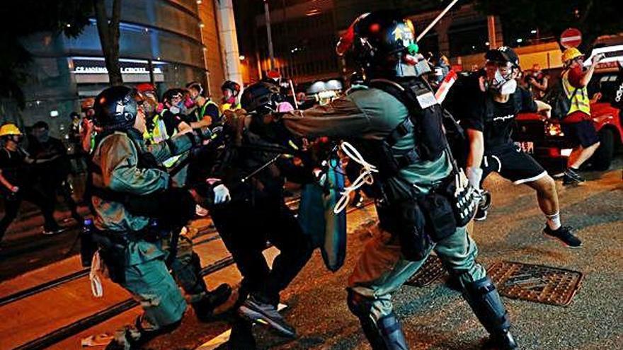 Dos policies colpegen un manifestant durant les protestes a Hong Kong.