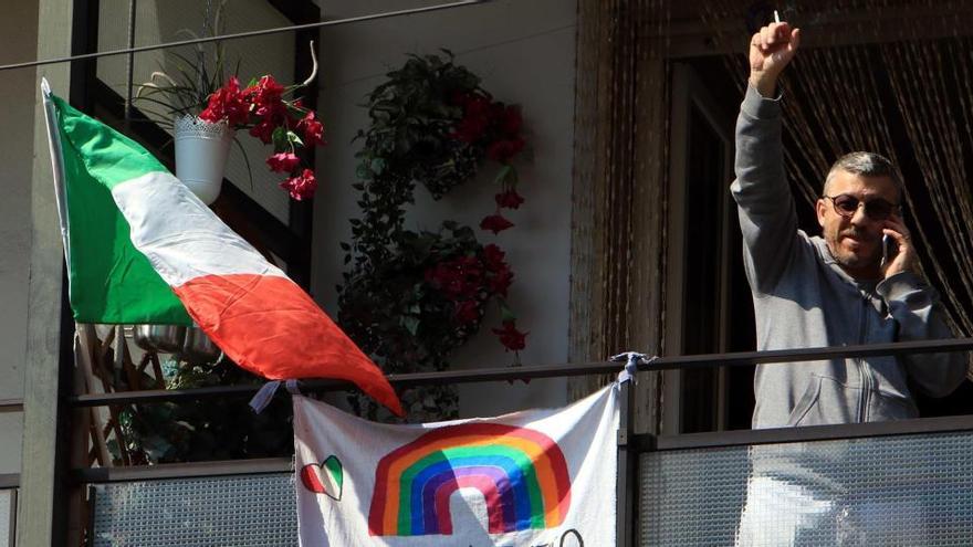 Un hombre levanta la mano desde su balcón en Milán.