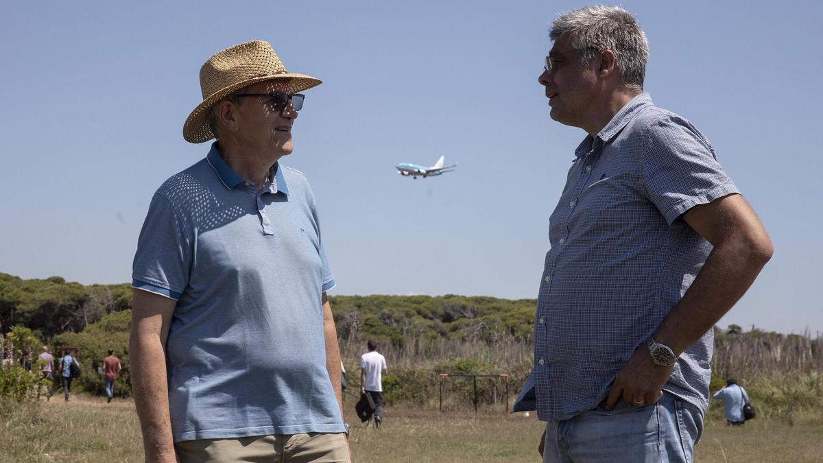 Narcís Prat (izquierda) y Joan Roig charlan junto al estanque de La Ricarda, en el momento en el que un avión se dispone a tomar tierra en el aeropuerto