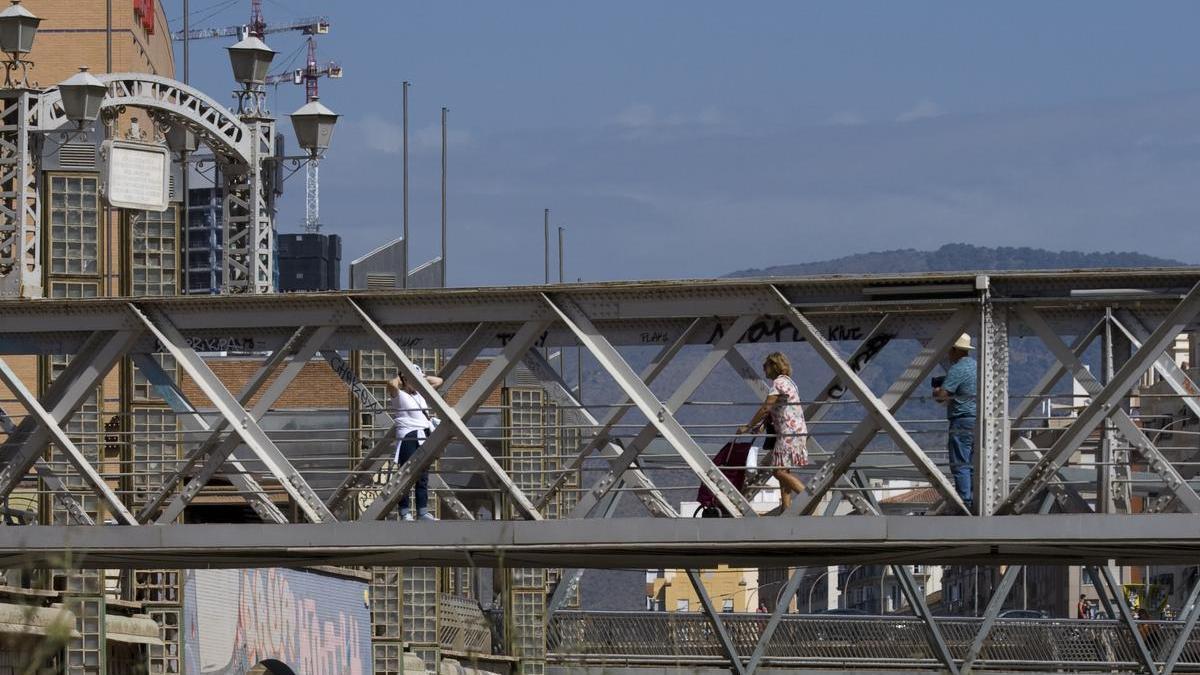 Varios peatones cruzan el Puente de los Alemanes, o de Santo Domingo, sobre el río Guadalmedina