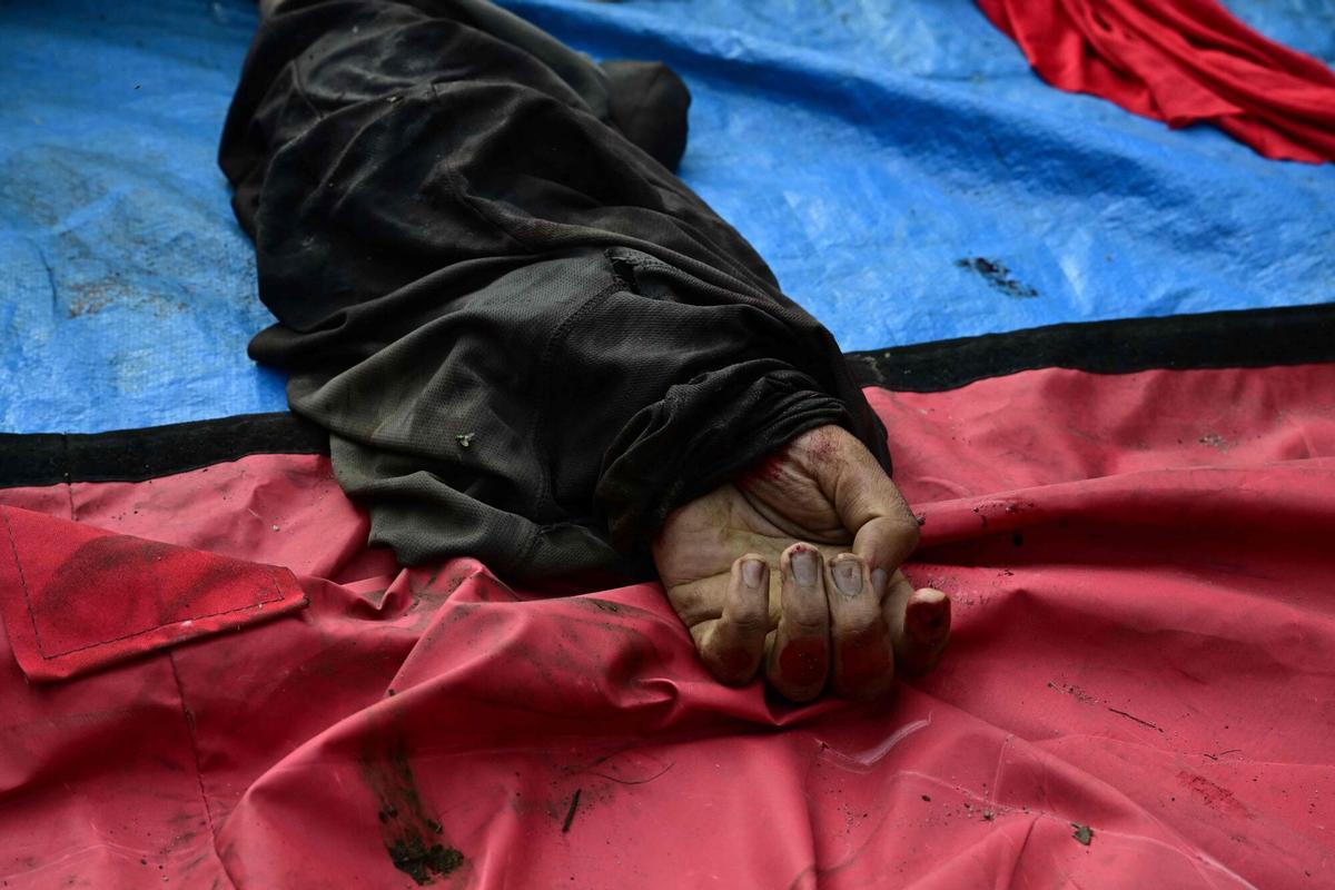 EDITORS NOTE: Graphic content / The hand of a dead man is seen among a line of bodies on Sao Lucas Square of the Vila Cruzeiro favela at the Penha complex in Rio de Janeiro, Brazil, on October 29, 2025, in the aftermath of Operacao Contencao (Operation Containment). Residents of a favela in Rio de Janeiro lined up more than 50 bodies at a plaza in their low-income neighborhood on Ocotber 29, a day after the bloodiest police operation in the citys history, AFP reported. (Photo by Pablo PORCIUNCULA / AFP). Graphic content