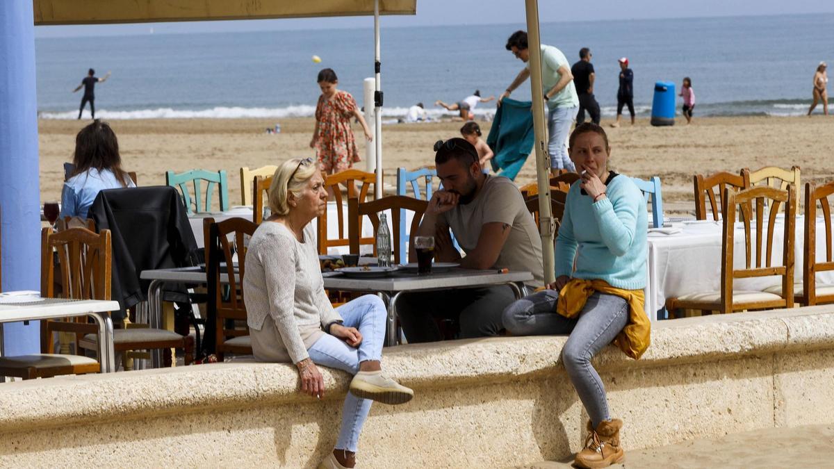 Mujeres fumando, ayer, junto a la terraza de un negocio de la playa de València.