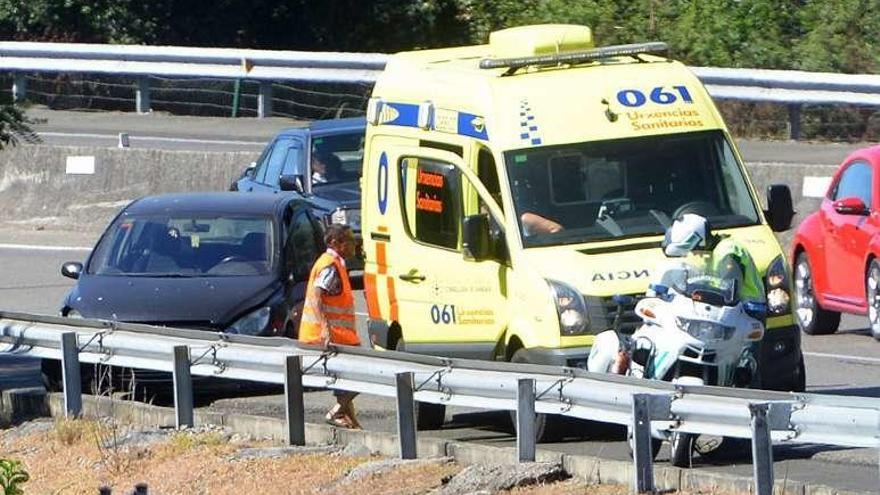 Una ambuancia junto mal coche accidentado en la AP-9. // G. Santos