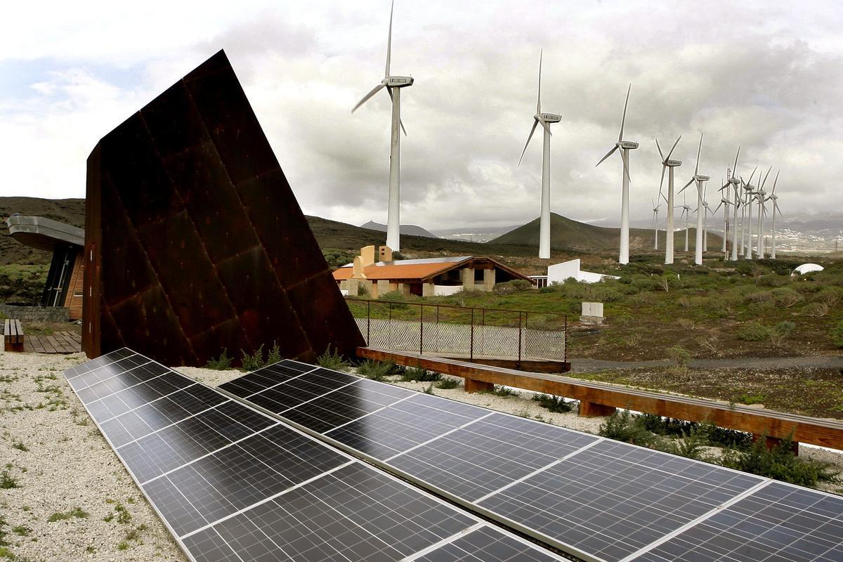 Placas solares junto a un parque eólico.