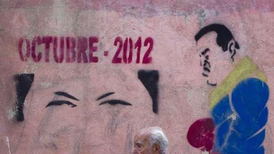 Un hombre pasa junto a un grafiti electoral de Chávez de octubre.  // Efe