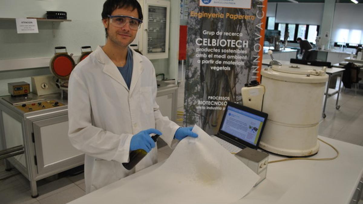 El joven investigador Oriol Cusola, del grupo de investigación CelBiotech de la UPC, aplicando la nueva sustancia, con un spray, un material de base celulósica.